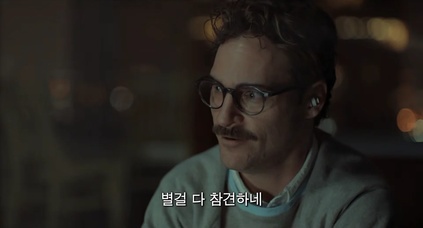 테오도르가 이어폰을 낀 채 이동하며 사만다와 음성으로 대화하는 영화 장면입니다.